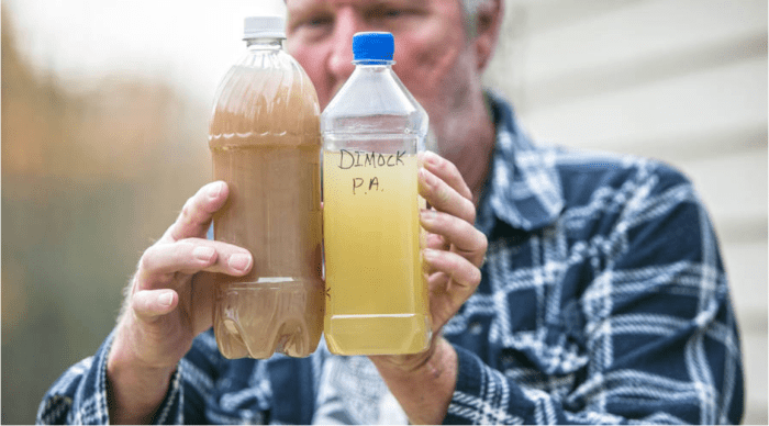 Ray Kemble holds two samples of well water from his neighborhood in Dimock, PA. He says the water was contaminated after fracking. - Amanda Hrycyna for APM Reports