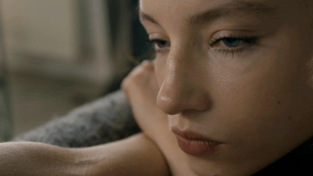 Close-up of a young woman's face with a contemplative expression, focusing on her eyes and lips.