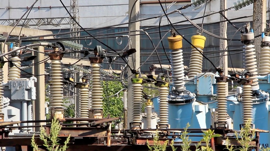 A close-up view of electrical infrastructure, featuring transformers, insulators, and numerous wires in an industrial setting.